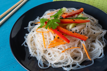cellophane noodles on a plate on a wooden table with vegetable sauce and dressing