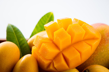 Fresh and beautiful mango fruit set in a wooden box with sliced diced mango chunks isolated on a...