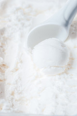 Fototapeta na wymiar Scoop of creamy vanilla ice cream with a white spoon for ice cream