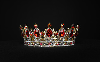 portrait of a beautiful jewelled ruby, diamond and golden crown, photographed on a black studio...