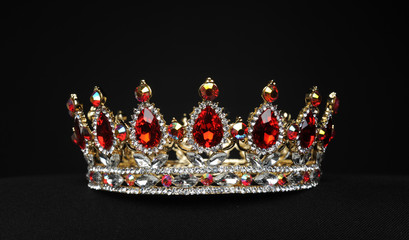 portrait of a beautiful jewelled ruby, diamond and golden crown, photographed on a black studio...