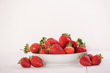 red ripe strawberries on white background in a bowl