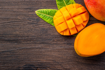 Fresh and beautiful mango fruit with sliced diced mango chunks on a dark wooden background, copy...