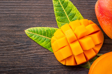 Fresh and beautiful mango fruit with sliced diced mango chunks on a dark wooden background, copy space(text space), blank for text, top view.