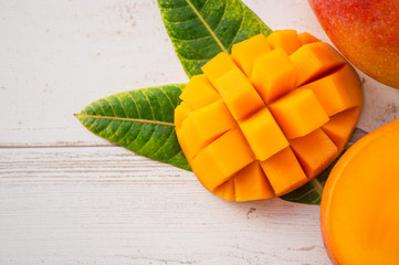 Fresh and beautiful mango fruit with sliced diced mango chunks on a light wooden background, copy space(text space), blank for text, top view.