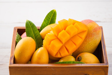Fresh and beautiful mango fruit set in a wooden box with sliced diced mango chunks on a light wooden background, copy space(text space), blank for text