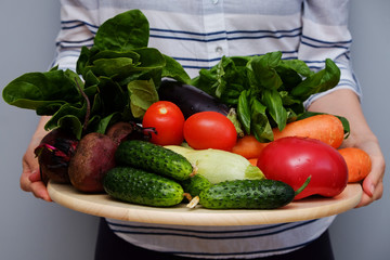 Woman's hands holding tray with fresh colorful vegetables. Healthy food concept.