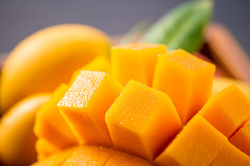 Fresh and beautiful mango fruit set in a wooden box with sliced diced mango chunks on a dark wooden background, copy space(text space), blank for text