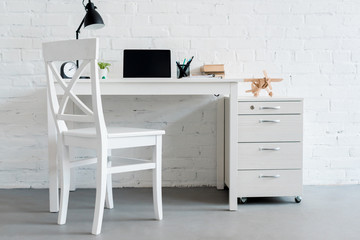 modern work desk with laptop at home in front of white brick wall