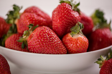 red ripe strawberries on white background in a bowl