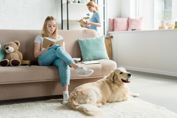 focused mother and teen daughter reading books together at home