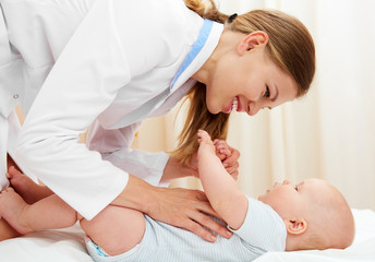 Obraz na płótnie Canvas Smiling female practitioner examining baby girl in medical office. 