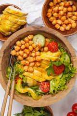 Grilled chicken salad with vegetables and chickpeas in a wooden bowl on a white background. Healthy balanced diet concept.