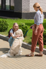 mother and daughter spending time together on street with their dog
