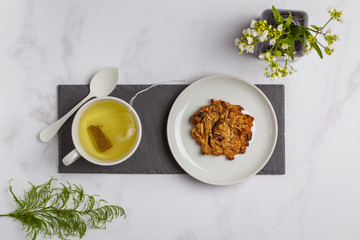Green (herbal, white) tea with vegan oat cookies on white background. Flat lay food, copy space, top view