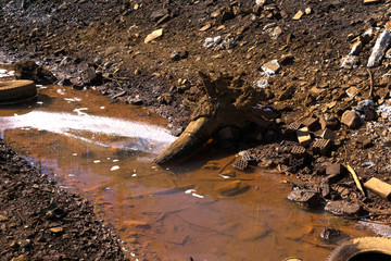 Heavy polluted water stream with domestic garbage .
