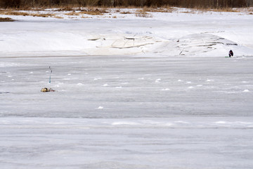Fisherman sitting in winter on ice .
