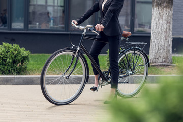 cropped shot of businesswoman in suit with retro bicycle on street