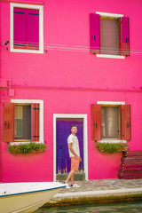 man at an pink house walking at Burano Venice Italy 