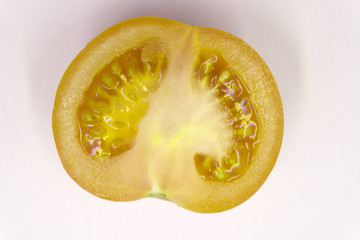 Slices of eggplant with cloves of garlic and a half of tomato on a wooden board surface.