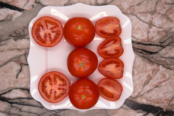Group of fresh ripe whole and cut tomatoes with kitchen knife on vintage black surface. Top view point.