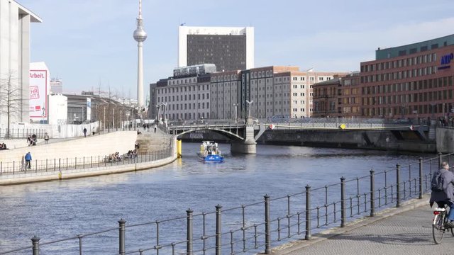 Berlin city center river and buildings, TV tower and people tourists walk ride bicycles