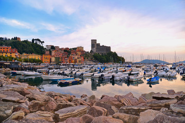 Fototapeta na wymiar colorful boats and seascape with old castle and blue cloudy sky with sunset in Lerici in Liguria, Italy
