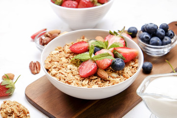 Serving option of granola bowl with mix of nuts, cereals, fruits and berries, greek yogurt. Healthy vegetarian breakfast, organic strawberry, blueberry, mint, almond. Close up, top view, background.