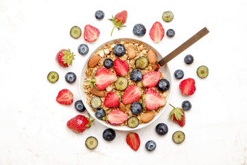 Serving option of granola bowl, mix of nuts, cereals, fruits & berries, greek yogurt, spoon. Healthy vegetarian breakfast, organic strawberry, blueberry, mint, almond. Close up, top view, background.