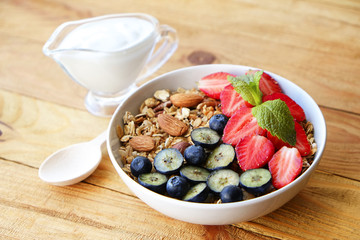 Serving option of granola bowl with mix of nuts, cereals, fruits and berries, greek yogurt. Healthy vegetarian breakfast, organic strawberry, blueberry, mint, almond. Close up, top view, background.