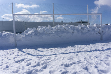 football goal littered with snow winter field .