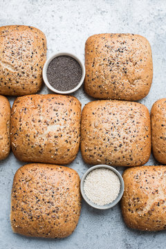 Multigrain bread rolls and bowls of seeds, overhead view