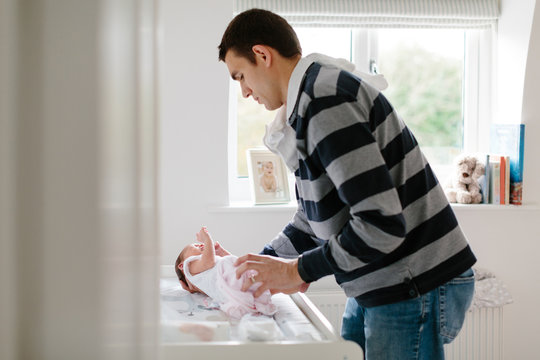 Father dressing newborn baby