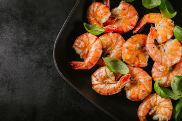Grilled king prawns on pan on dark table