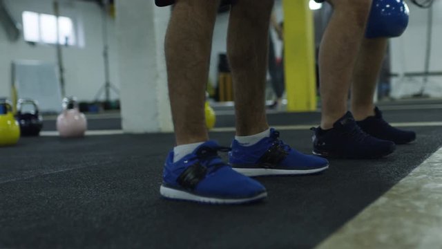Strong muscular athletes working out training with kettlebells.