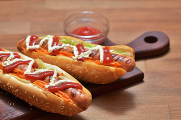 Two hot dogs with barbecue sausage with sauces and greens