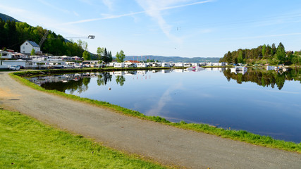 Lakeside camping site on a sunny and windless morning. Boat in the marina and wake park jumps in the water. Logos and id removed.