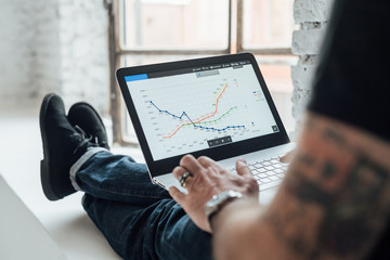 Man looking at graphical data on laptop