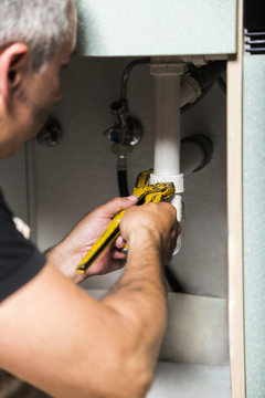 specialist male plumber repairs faucet in kitchen