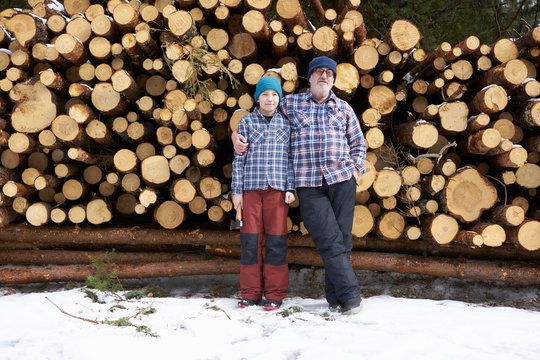 Portrait of father and son, in front of  stack of logs