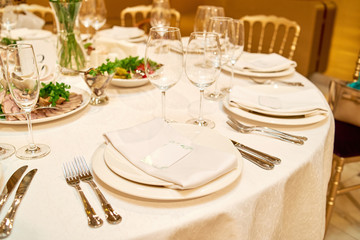 Table setting with blank guest card on empty white plate and cutlery on table, copy space. Menu mockup, place setting at wedding reception. Table served for wedding banquet in restauran