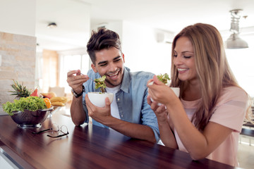 Obraz na płótnie Canvas Couple eating a salad in the kitchen