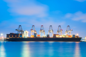Fototapeta premium Container Cargo freight ship with working crane bridge in shipyard at dusk for Logistic Import Export background