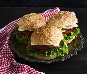 three burgers with a meat chop, vegetables and cheese