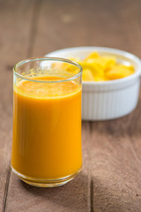 Mango smoothie with mango slice on wooden table