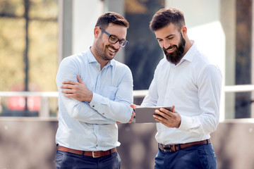 Two business people outside looking  tablet