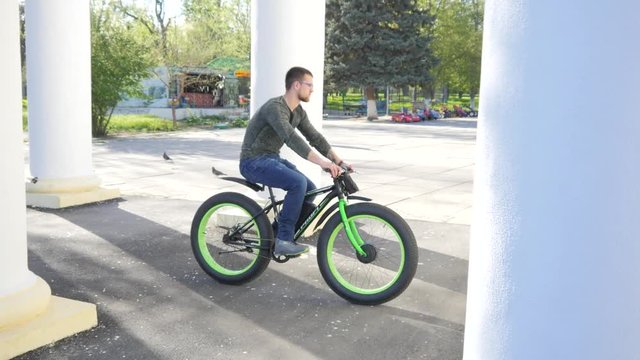 Man rides pedals Electric bicycle in a public park place