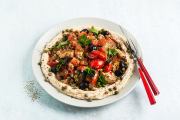vegan panzanella salad on a layer of hummus on a plate. tasty healthy food.