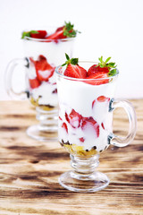 Tasty sweet dessert with yogurt and fresh strawberry on a rustic table on a white background