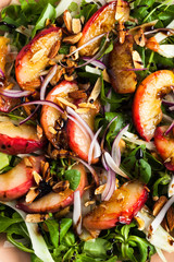 summer, very tasty salad with peaches, sweet onions and arugula with almonds on a table in a plate. simple healthy recipe